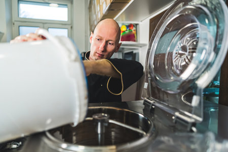 Pouring ice cream from a bucket to pasteurization machine ice cream preparation. High quality photoの写真素材