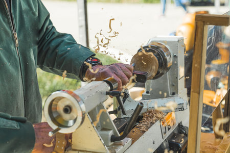 Male artist carpenter creating art on a woodturning lathe. Machinery used in carpentry. Sawdust during woodturning. Outdoor shot. Hillegom. High quality photoの写真素材