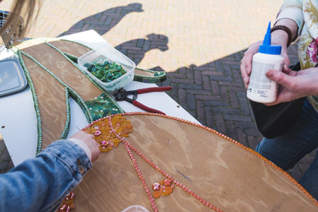 Mosaic art pieces made from recycled plastic, glass and other materials. Two people decorating...