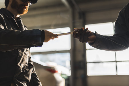 Car mechanics passing a wrench to each other. High quality photoの写真素材