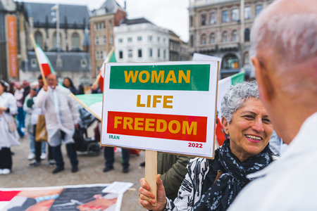 04.18.2023 Amsterdam, Netherlands. Positive short-haired female protester with a poster - woman, life, freedom - made with Iranian flag colors. High quality photoのeditorial素材