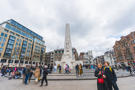 02.26.2023 Amsterdam, Netherlands. Tourist standing on Dam central square during the morning in the old town of Amsterdam city. High quality photoのeditorial素材