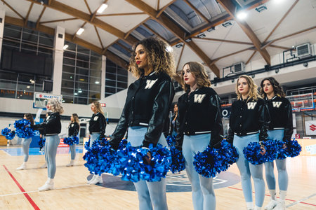 Cheerleader girls team standing in lines with pompons in front of them on a court. High quality photoの写真素材
