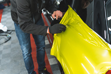 High angle show of a man in black protective glove during a process of car wrapping. Changing car colour without paint respray. . High quality photoの写真素材