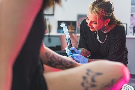 tattoo artist girl drawing a new tattoo and talking to her client, medium shot. High quality photoの写真素材