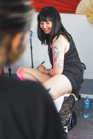 cheerful client sitting on a table and waiting for a tattoo master to start working on a new tattoo. High quality photoの写真素材