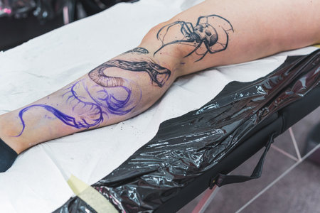 process of creating a new tattoo on a customers leg, snake tattoo. High quality photoの写真素材