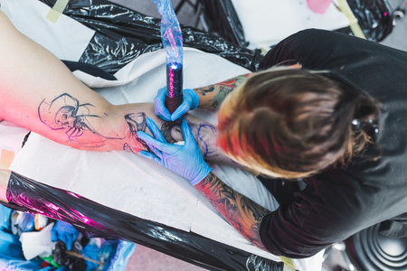 top-down shot of a tattoo artist making black and white tattoo on a womans leg. High quality photoの写真素材