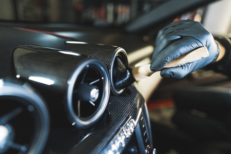 Car ventilation being cleaned with professional car detailing brush bu an unrecognisable deep-cleaning expert in protective black glove. High quality photoの写真素材