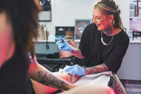 young and pretty tattoo master girl enjoying while working in her studio, medium shot. High quality photoの写真素材
