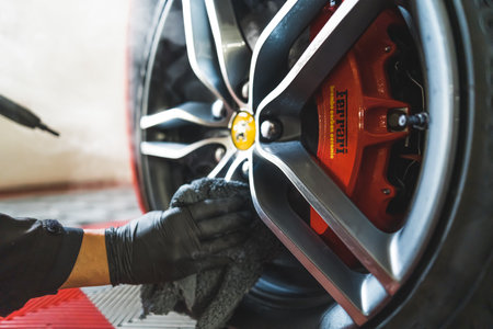 05.17.2023 Warsaw, Poland. Cleaner disinfecting car wheels and tyres with steamer closeup. Male car detailing specialist drying up Ferrari wheel. High quality photoのeditorial素材