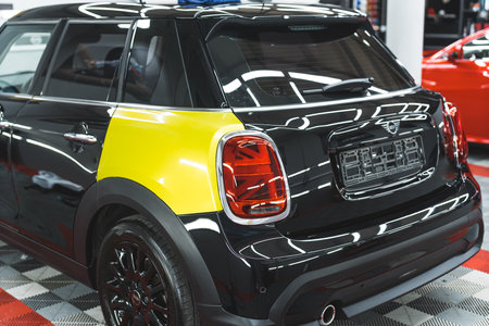 05.17.2023 Warsaw, Poland. Back view of a black Mini Cooper during car wrapping process. Changing colour from black to neon yellow. High quality photoのeditorial素材