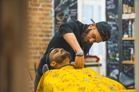 Barber trimming the neck hair of a client using a hair clipper in a modern salon. High quality photoの写真素材