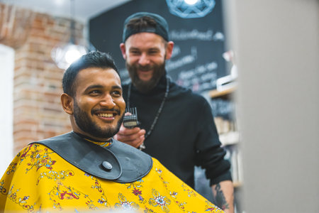 Happy Indian male client after a haircut with a barber behind him in barbershop. High quality photoの写真素材
