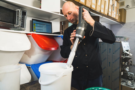 Churning ice cream using professional blender. Ice cream making concept. Male professional whipping up ice cream in big bucket. High quality photoの写真素材