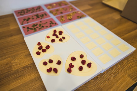 Selection of premium decorated chocolate in moulds. WHite chocolate wth raspberries. Ruby chocolate with pistacchio and walnuts. Indoors closeup shot. High quality photoの写真素材