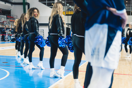 Cheerleaders team standing with blue pompons on a basketball court. High quality photoの写真素材