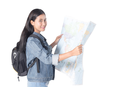 Portrait of a joyful asian woman hiker open worldmap in the studio while carrying a backpack, isolated on white background, 20-28 year old.の写真素材