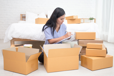 Young asian woman business owner work and white down address for deliver at home, woman business owner concept, 20-25 year old..の写真素材