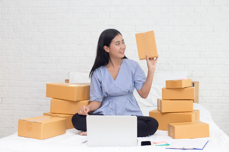 Young asian woman business owner work and white down address for deliver at home, woman business owner concept, 20-25 year old.の写真素材