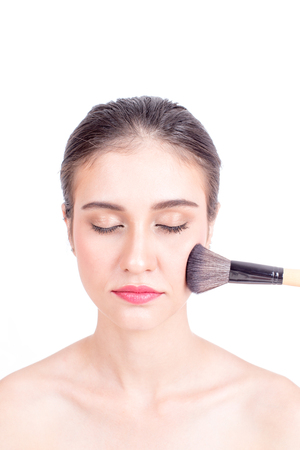 Makeup artist applies brushed at woman face. Beautiful woman face. Perfect makeup, isolated on white background, 20s year old.の写真素材