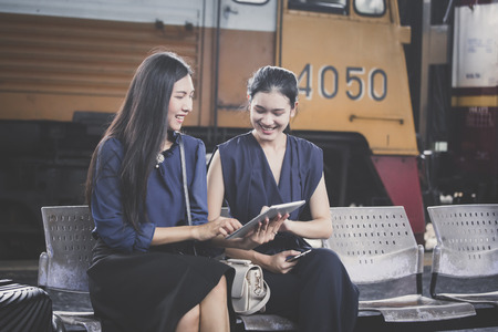 Two asian woman using tablet at outdoor place with attractive smiling, woman resting concept.の写真素材