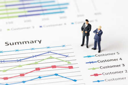 Miniature model group of businessman thinking with project for investment standing together on paper graph.の写真素材