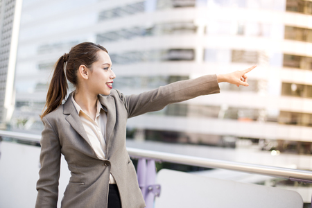 Young asian businesswoman pointing direction to the future with attractive smiling at city. woman reader concept, 20-30 year old.の写真素材