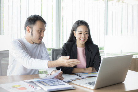 Asian man present project for woman at office place, people working concept, 20-30 years old.の写真素材