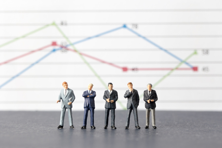 Miniature model group of businessman thinking with project for investment standing together on paper graph.の写真素材