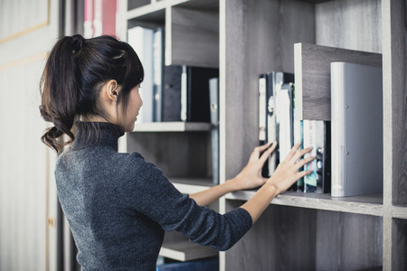Asian woman searching document at working place, woman working concept, vintage tone.の写真素材