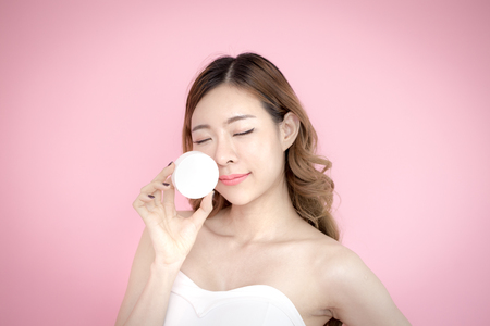Young beautiful korea woman holding product in hand with relax emotion at pink background, 20-30 year old.の写真素材