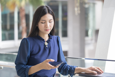 Young asian woman using smart phone at outdoor place.の写真素材