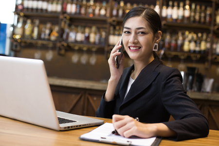 Asian Woman using Smartphone in restaurant with Attractive Smiling, Woman working Conceptの写真素材