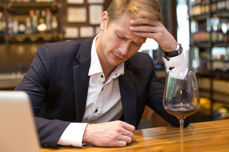 Businessman Hangover suffering when he drunk wine at Bat, Man with alcoholism concept.の写真素材