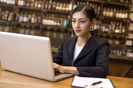 Asian Woman using laptop in restaurant for work, Woman working Concept