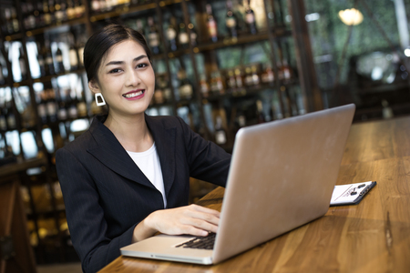 Asian Woman using laptop in restaurant with Attractive Smiling, Woman working Conceptの写真素材