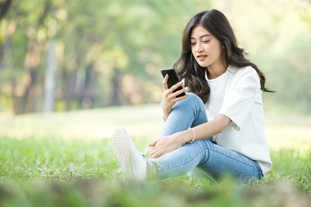 Asian Woman holding smartphone with attractive smiling at garden. People lifestyle concept.の写真素材