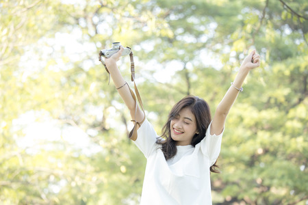 Attractive Asian woman holding retro camera with smiling, Woman using camera at outdoor place.の写真素材