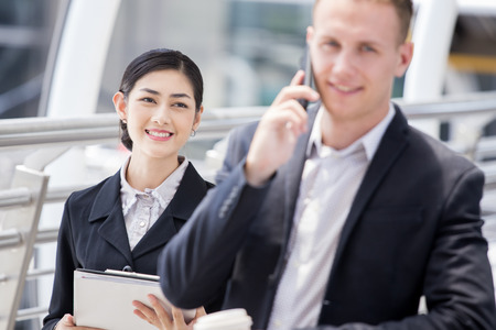 Happy Asian Businesswoman interesting to Assist Project with Businessman. People Working at outdoor place. Woman Working Concept.の写真素材