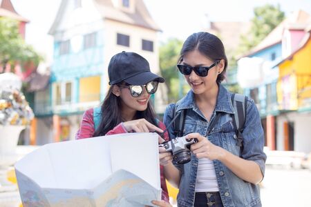 Portrait of Happy traveler Woman in city. Asian women expressing positivity, using map, vacation with bags, Happy emotions.の写真素材