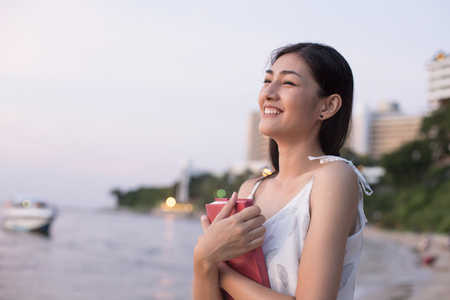 Asain Woman Holding Book at Beach, Woman Holding book with Attractive Smiling.の写真素材