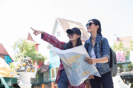 Portrait of Happy traveler Woman in city. Asian women expressing positivity, using map, vacation with bags, Happy emotions.の写真素材