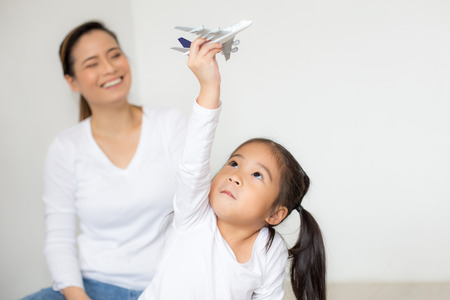 Asian Girl playing airplane at home. Kid playing airplane with Attractive smiling. People with travel concept.の写真素材