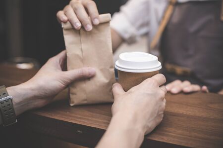 Hand of Barista making service to customer in the coffee shop. people with barista in cafe concept. Vintage tone.の写真素材