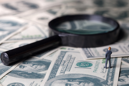 Miniature of investor man stand on money and magnifying glass in back. Business and Investment concept.の写真素材
