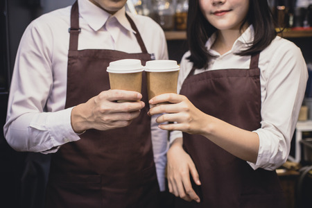 Closeup hand barista holding coffee cup in coffee shop counter. Barista working at cafe. Working people small business owner or sme concept. Vintage tone.の写真素材