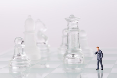 Miniature figurine toys standing on chess board. Focus on the businessman.の写真素材