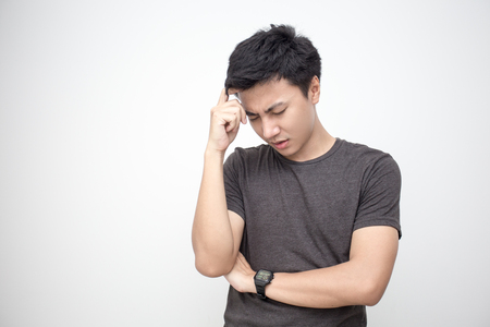 Man touching him head with hands. Young asian man feel headache. Isolated on white background.の写真素材