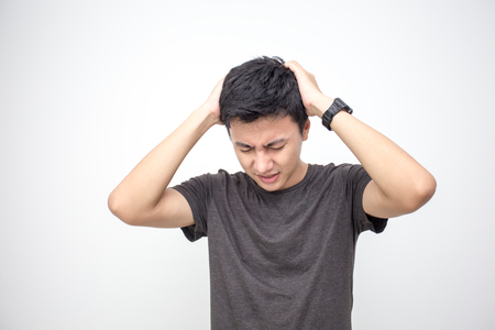 Man touching him head with hands. Young asian man feel headache. Isolated on white background.の写真素材